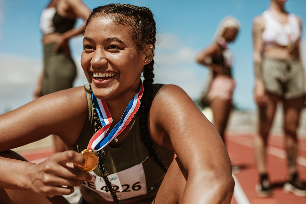 Vrouw houdt medaille vast op de atletiekpiste