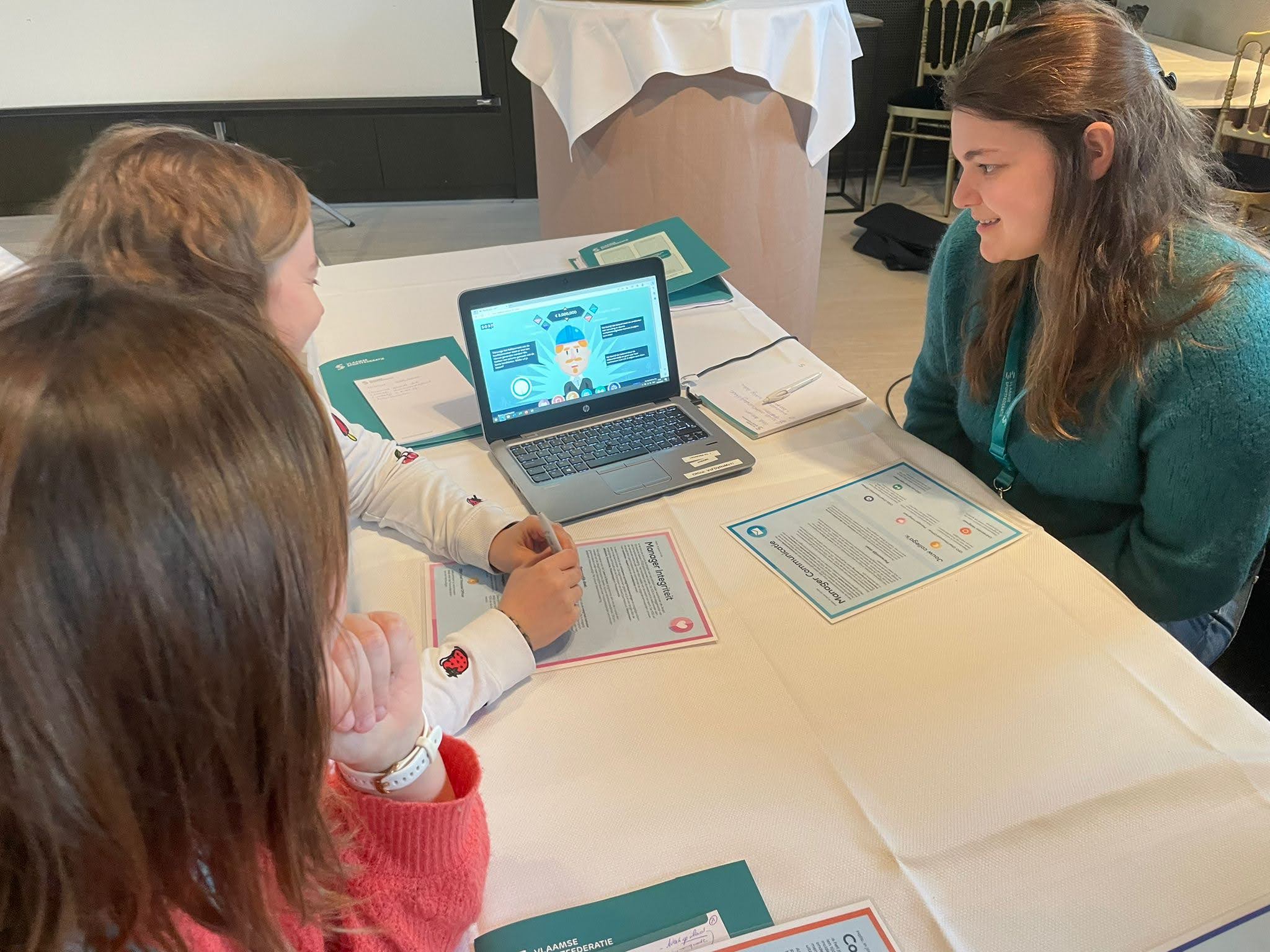 3 dames zitten aan tafel bij een laptop
