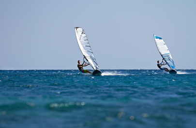 2 personen aan het windsurfen op zee