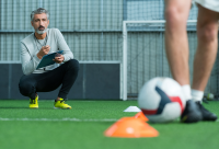 Coach zit naast een voetbalspeler